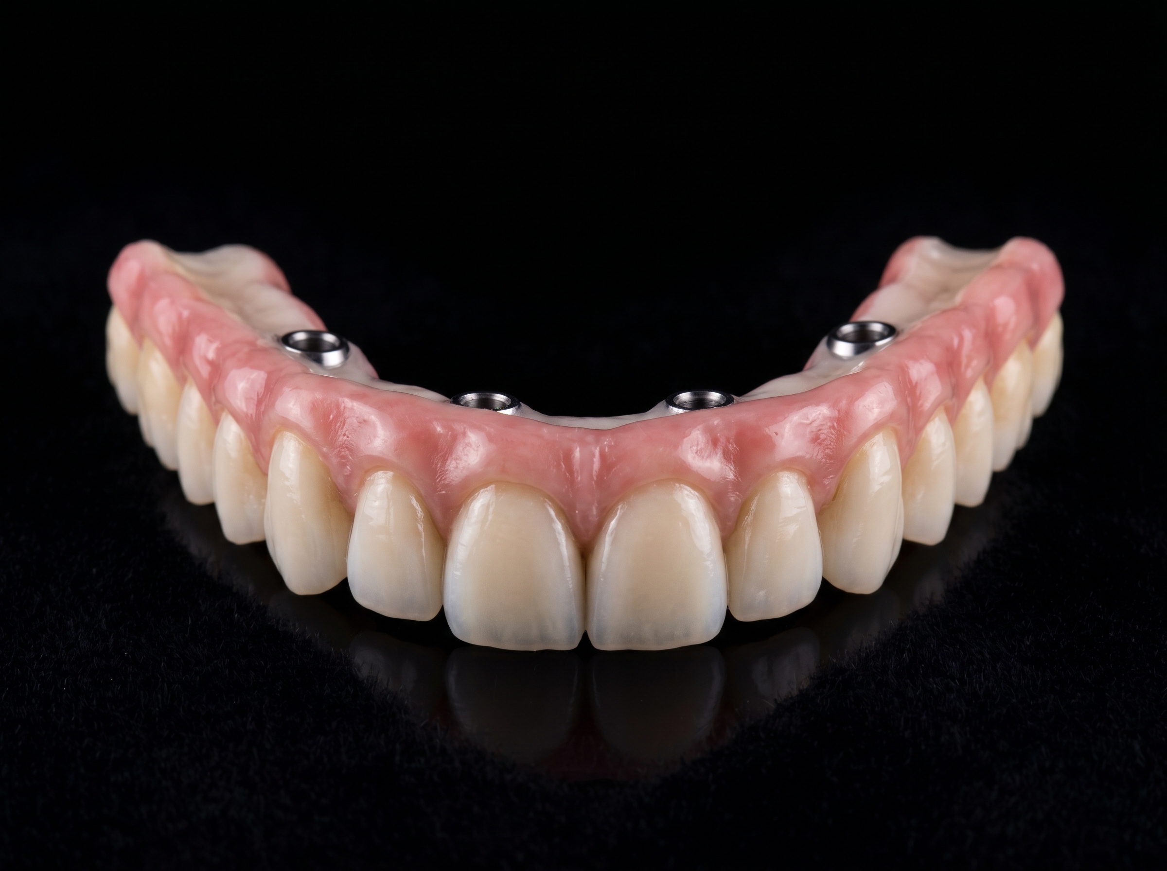 Finished zirconia All-on-4 dental bridge prosthesis on a black backdrop, museum-quality dental photography